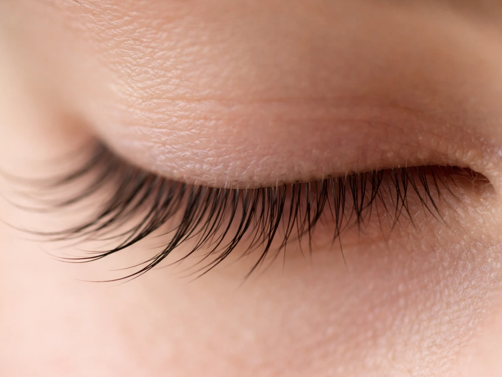 Close-up of an eyelash line showing mixed lash lengths—some longer, some shorter in natural light.